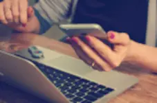 Cellulare in mano davanti a un notebook