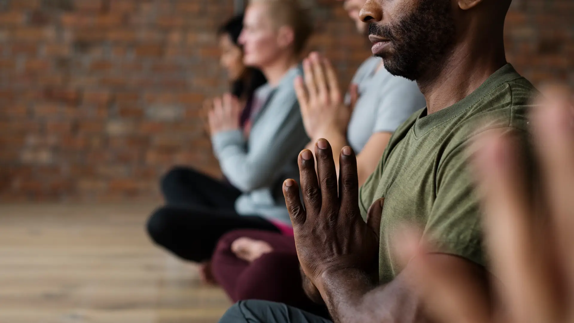 Persone sedute con le mani giunte al petto per ricevere una iniziazione Reiki, Energia Vitale Universale